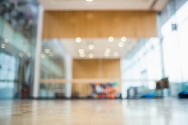 Unschärfeaufnahme eines Fitnessraums mit Holzfußboden und indirekter Beleuchtung im Hintergrund.