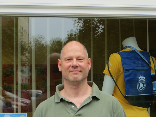 Mann mit kurzem Haar steht vor einem Schaufenster, in dem Sportbekleidung ausgestellt ist.