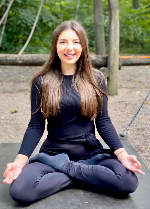 Frau mit langen Haaren im Schneidersitz mit Händen auf den Knien