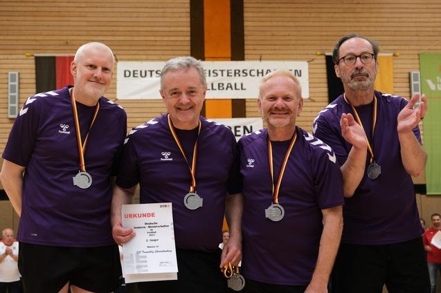 Vier männliche Tischtennisspieler in lila Trikots halten eine Urkunde und zeigen Medaillen in einer Sporthalle.