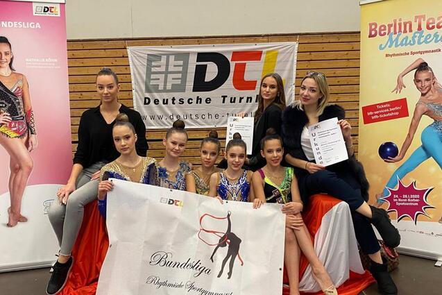 Gruppe junger Rhythmischer Sportgymnastinnen posiert mit Urkunden vor Banner des Berliner Masters und DTL.