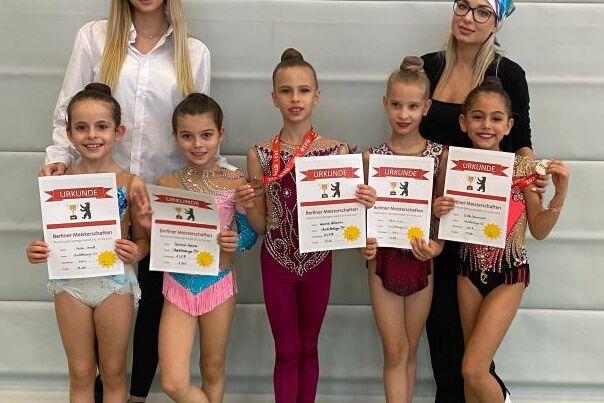 Sechswöchige Gruppenaufnahme von jungen Tänzerinnen mit Urkunden, posierend vor einer hellen Wand.