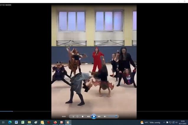 Gruppe von Tänzern in Kostümen führt eine Choreografie in einem Trainingsraum aus.