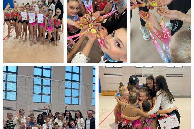 Gruppennahaufnahme von jungen Turnerinnen mit Medaillen und Urkunden in einem Sportraum. Sie feiern ihren Erfolg.