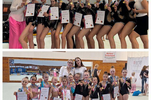 Zwei Gruppen von Tänzerinnen stehen in einem Sportraum, zeigen Medaillen und Urkunden, und posieren für ein Foto.