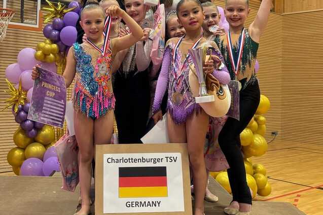 Gruppe von Turnerinnen mit Auszeichnungen und Medaillen auf dem Siegertreppchen beim Princess Cup in Deutschland.