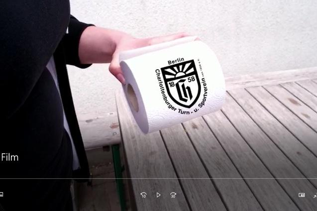 Eine Hand hält eine Rolle Toilettenpapier mit dem Logo des Charlottenburger Turn- und Sportvereins aus Berlin.