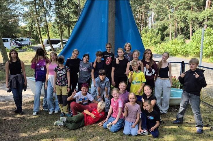 Gruppenfoto von Kindern im Freien vor einem blauen Tarp