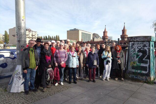 Gruppe von 30 Personen, die auf einem Platz vor einem Stadthintergrund mit Graffiti stehen.
