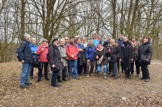 Gruppe von 20 Personen steht in einem Wald, umgeben von kahlen Bäumen, und posiert lächelnd für ein Foto.