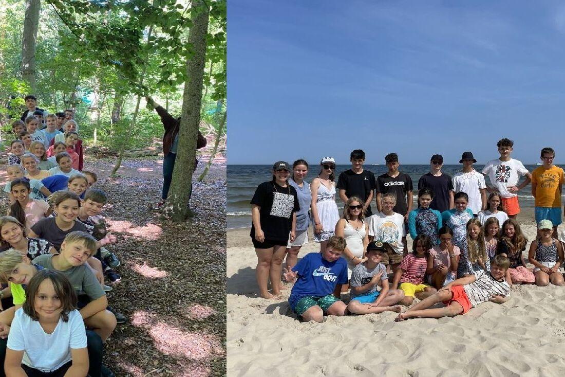 Gruppenfoto von Kindern und Jugendlichen am Strand, umgeben von Wasser und Sand, unter blauem Himmel.