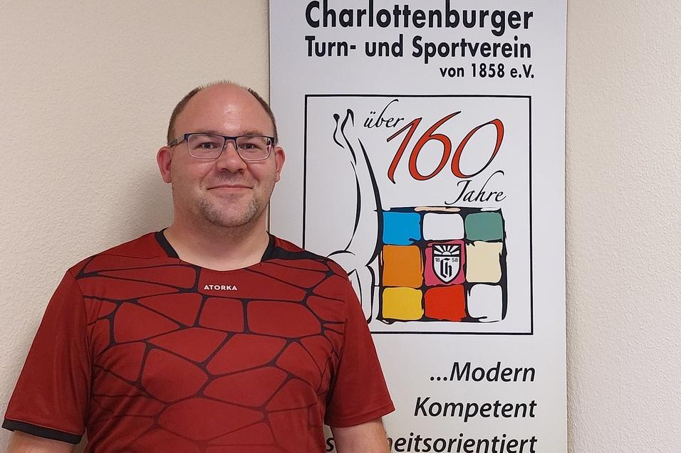 Mann mit Brille steht vor einem Banner des Charlottenburger Turn- und Sportvereins mit dem Hinweis auf 160 Jahre.