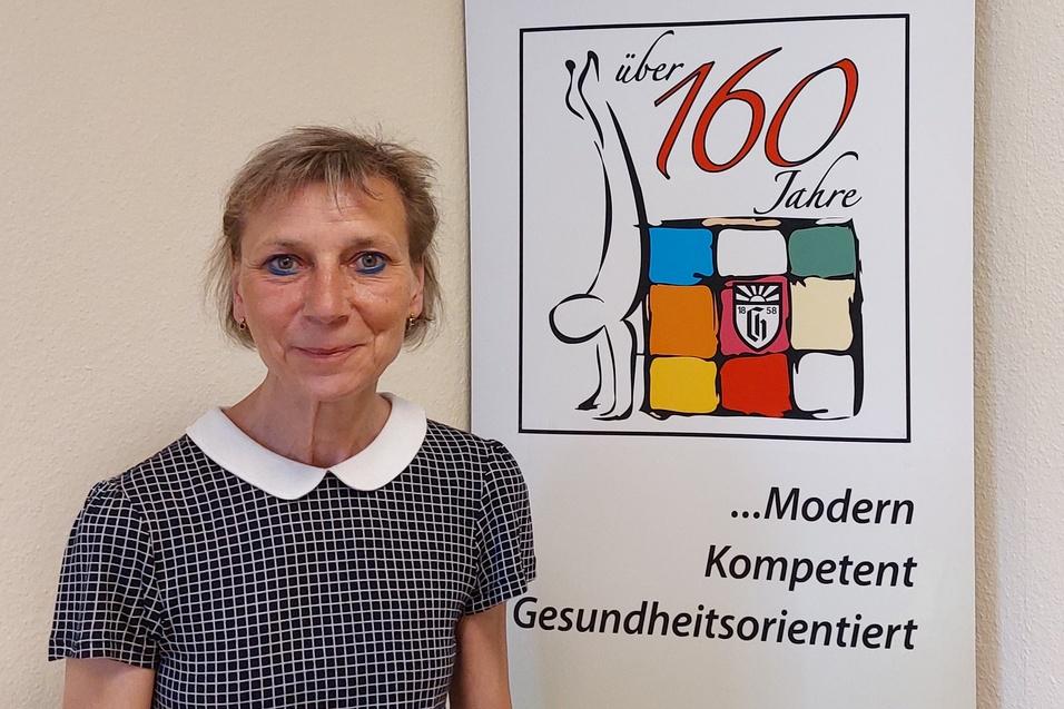 Frau mit Kurzhaarschnitt steht vor einem Banner des Charlottenburger Turn- und Sportvereins, 160 Jahre Jubiläum.